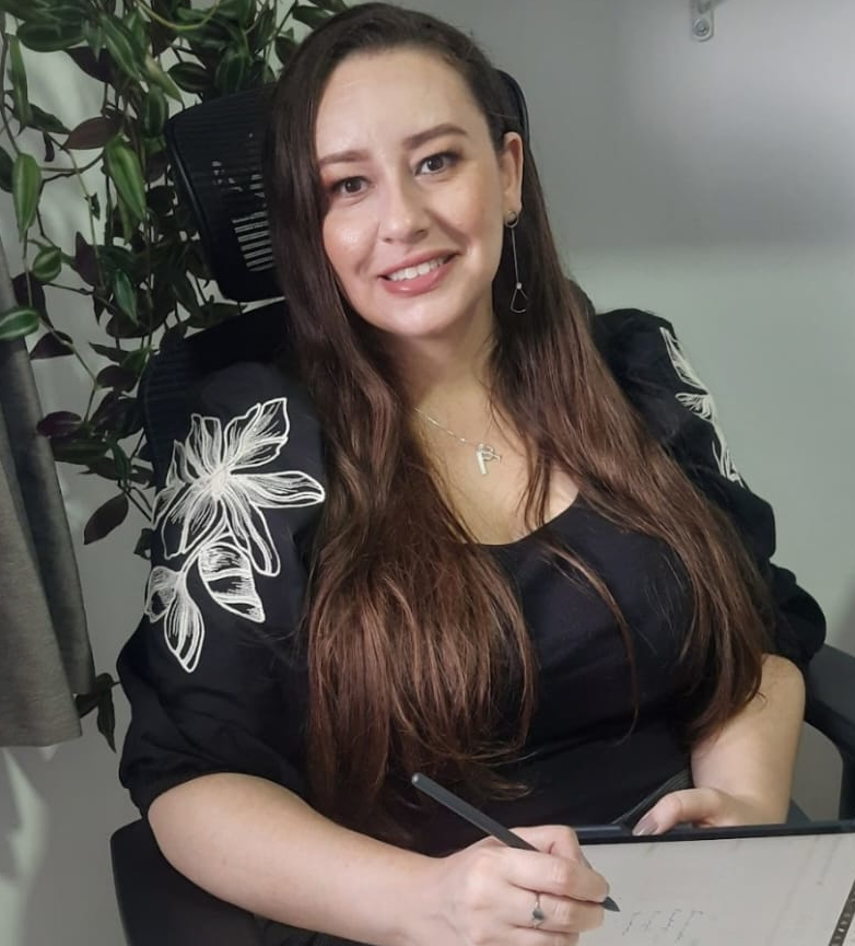Psicóloga Fernanda olhando para camera sorrindo, com planta ao fundo